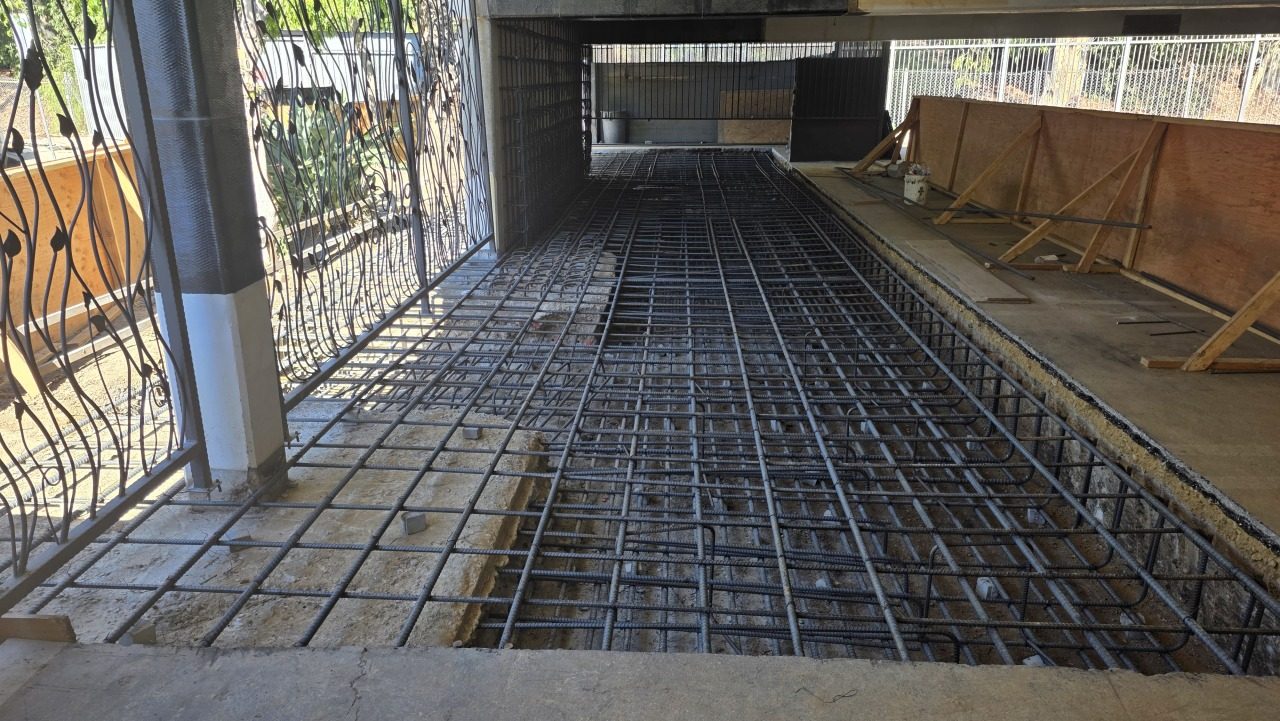 New slab rebar grid — footing excavation with ironwork gate visible